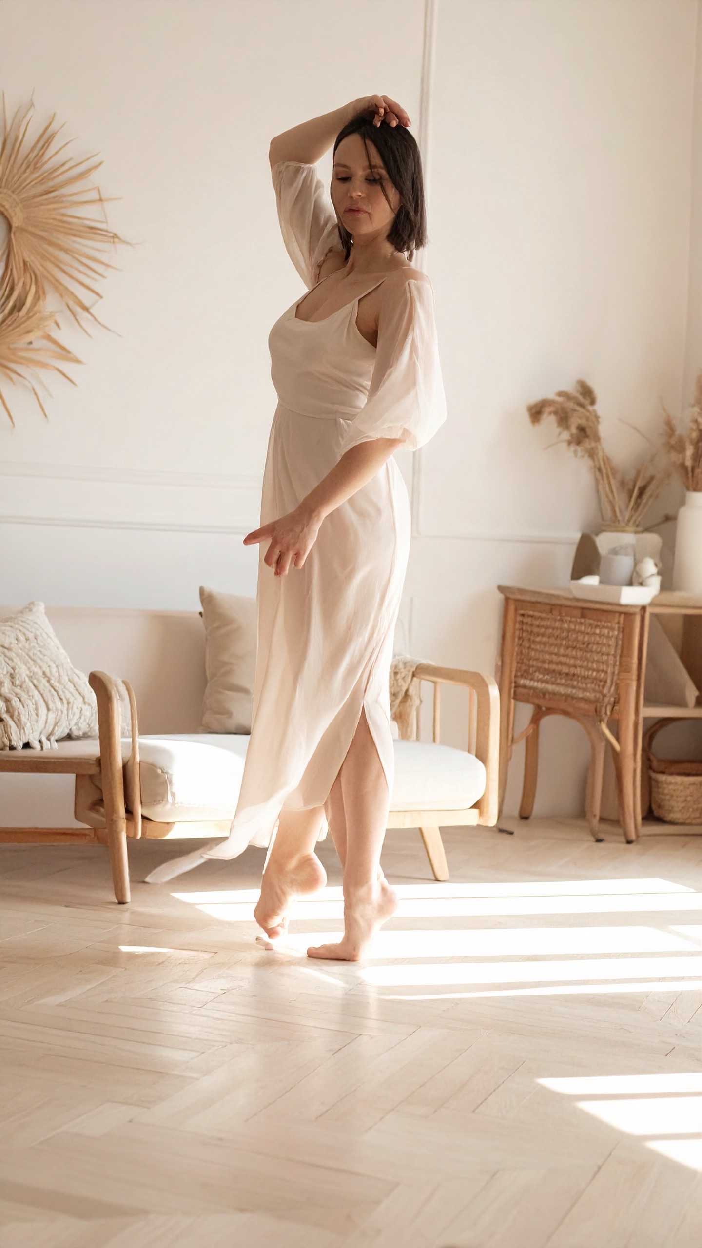 A woman turning barefoot across a sunlit parquet floor