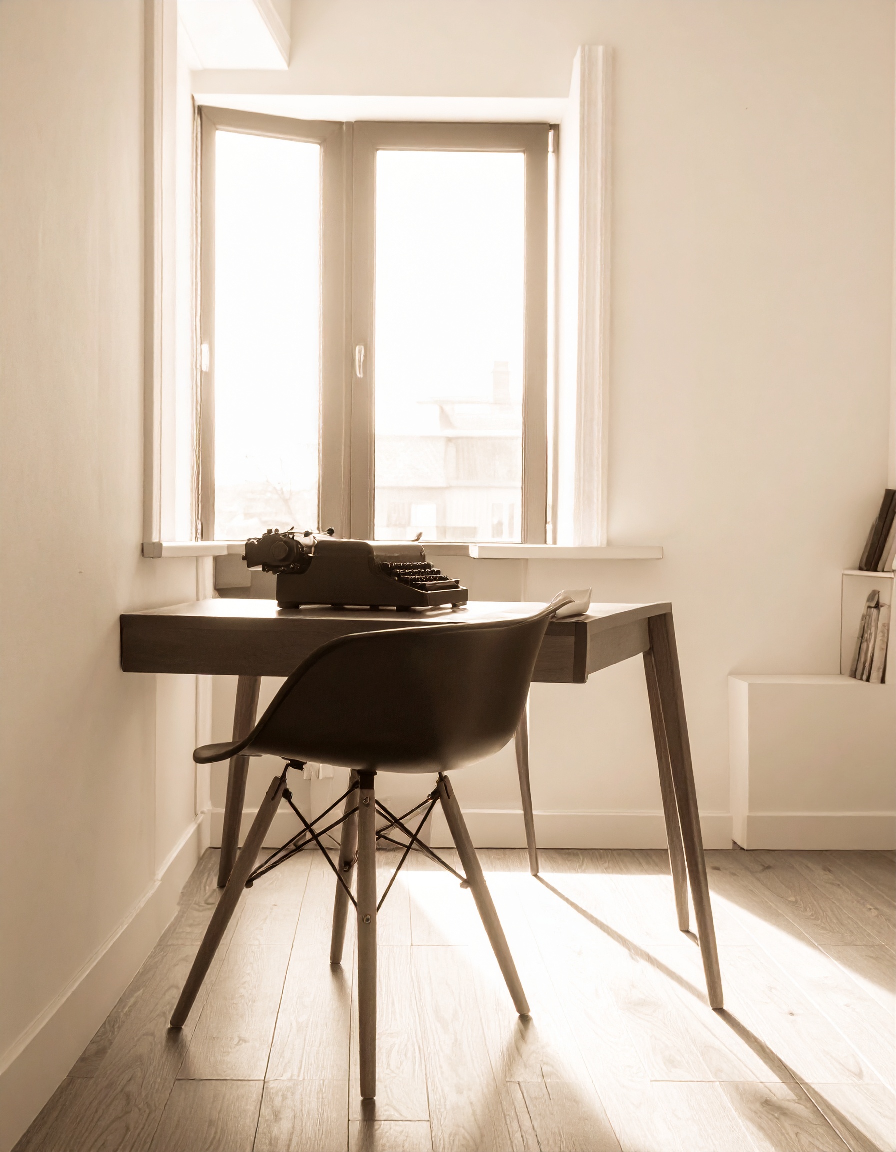 A typewriter on a desk at a bright window