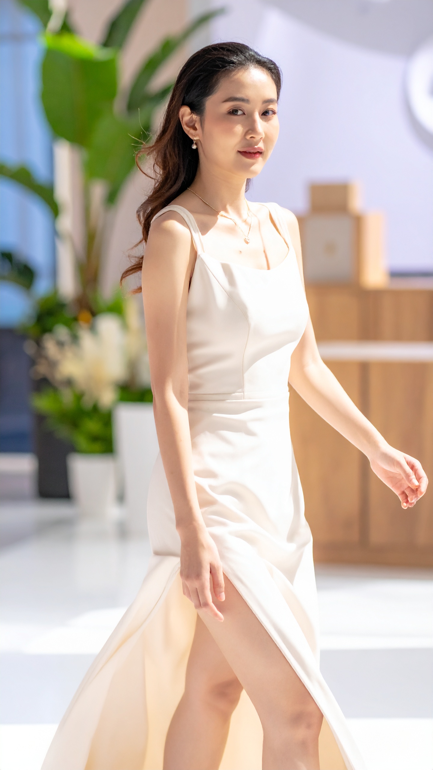 A woman in a cream gown mid-stride, her skirt caught sideways by moving air