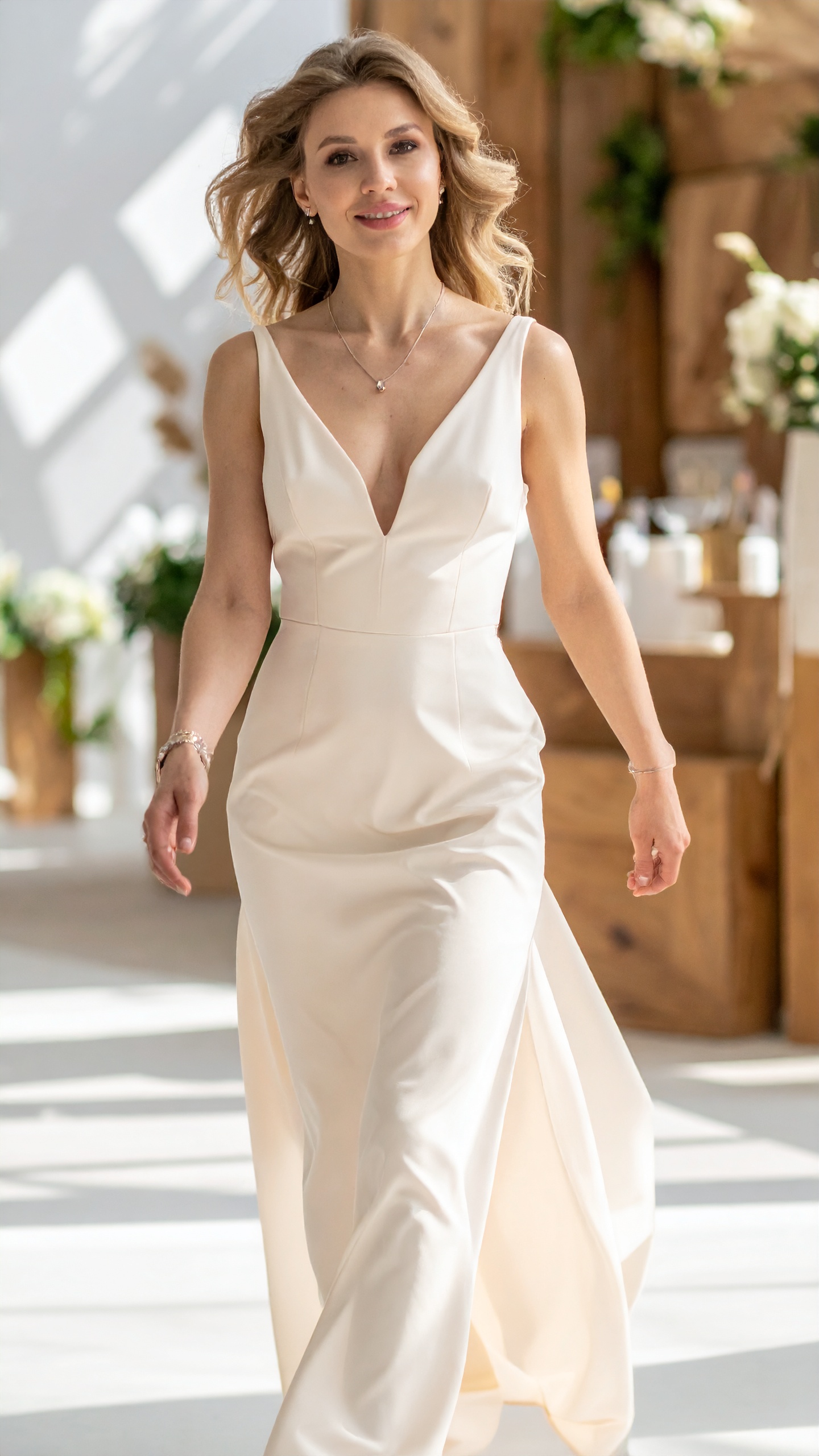 A woman mid-laugh in a pale gown, hair fully in motion, warm room behind