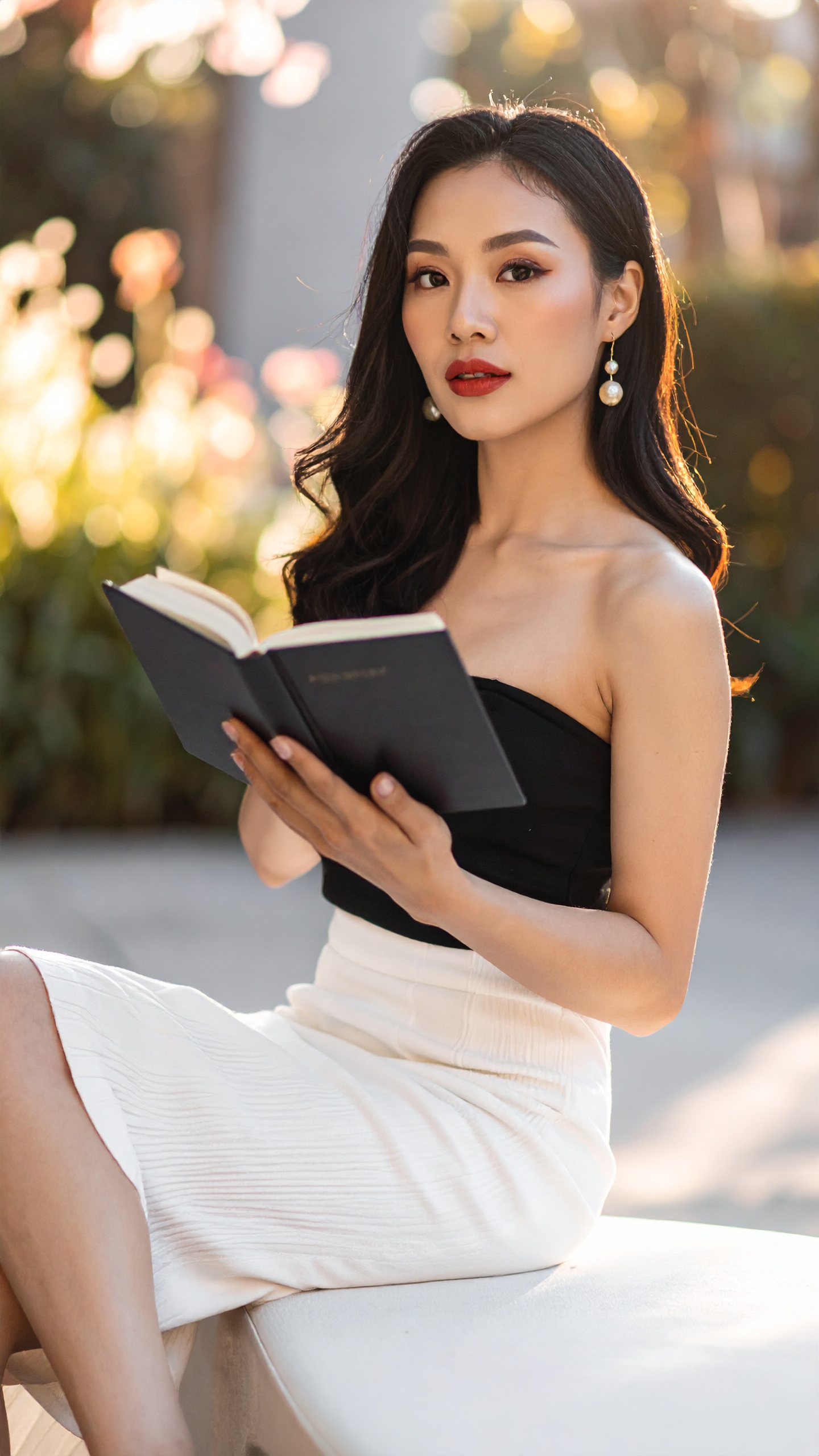 A woman in a pale gown seated in low golden light with an open book